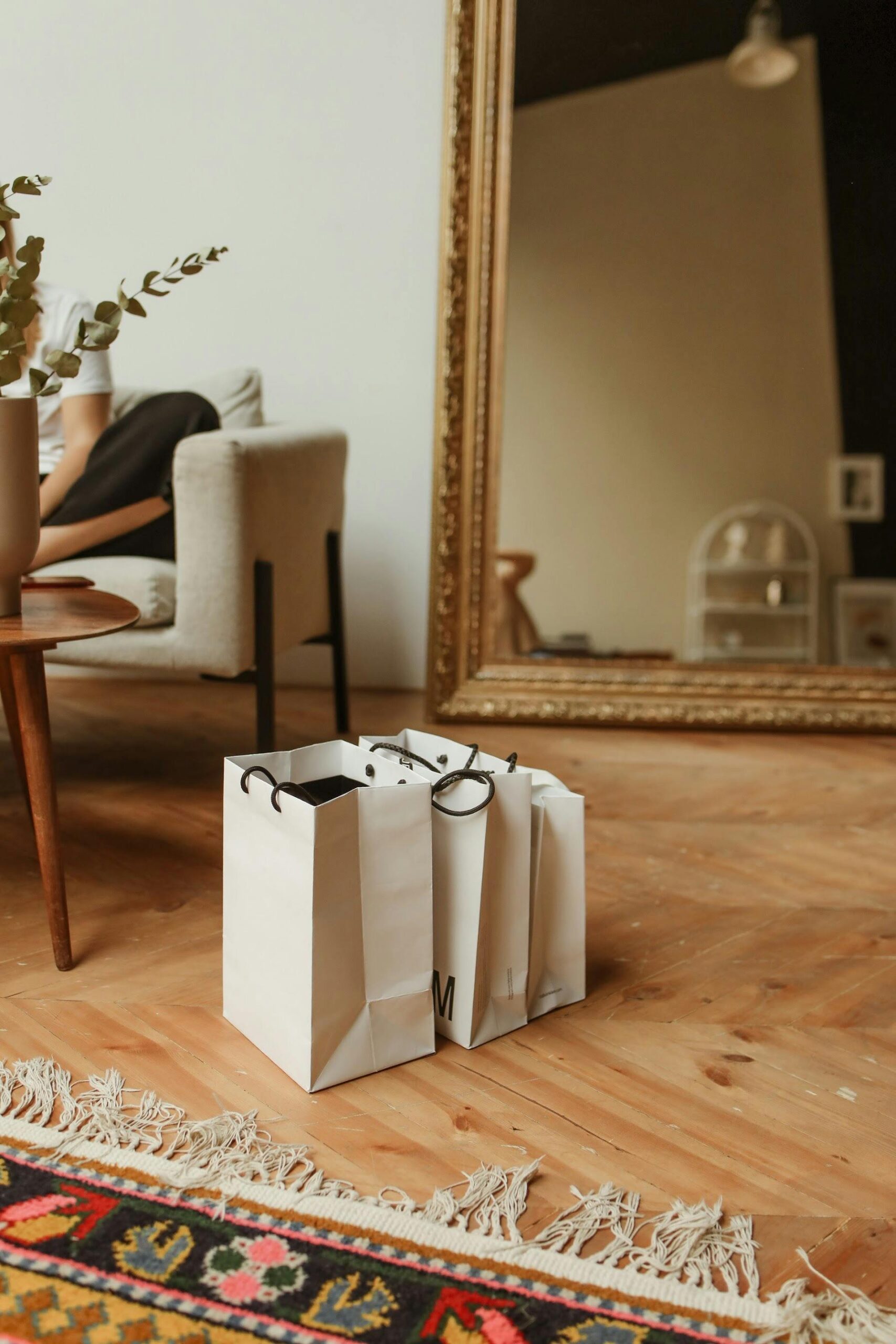 Modern living room with shopping bags and a large ornate mirror reflecting the decor.